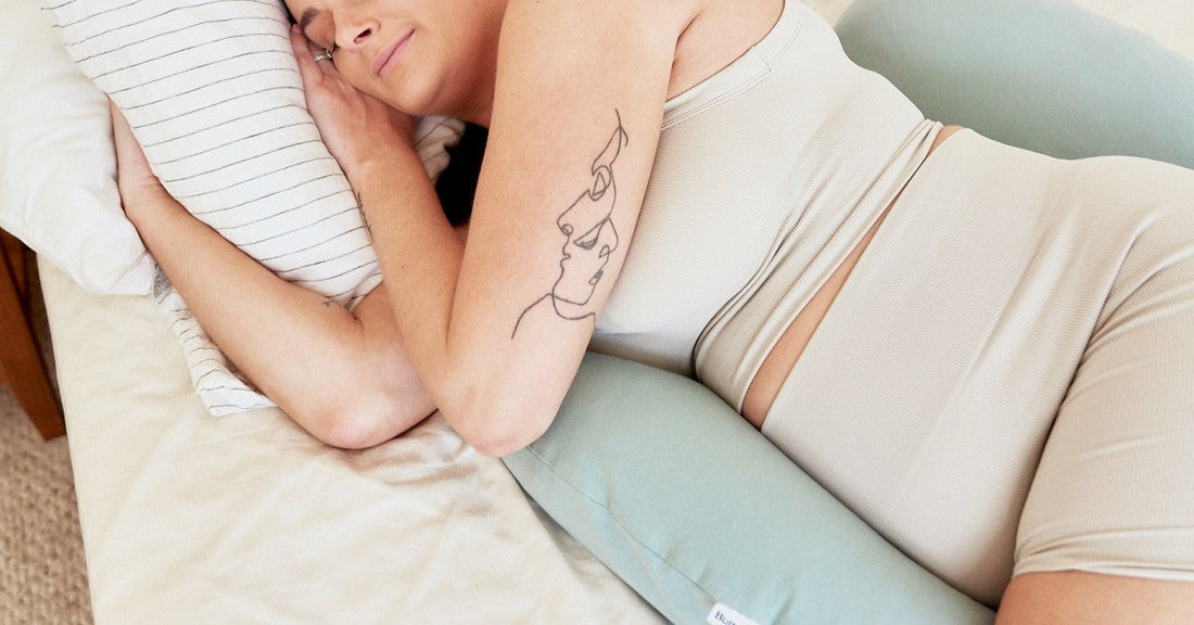 Pregnant woman sleeping on her side with a blue maternity pillow