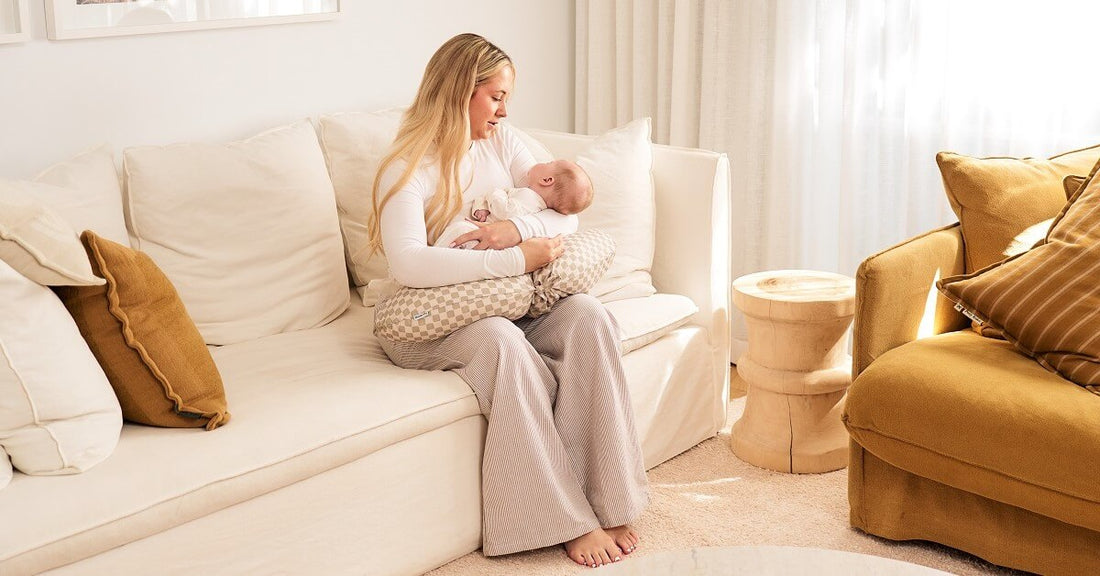 mum sitting on couch with her newborn baby 