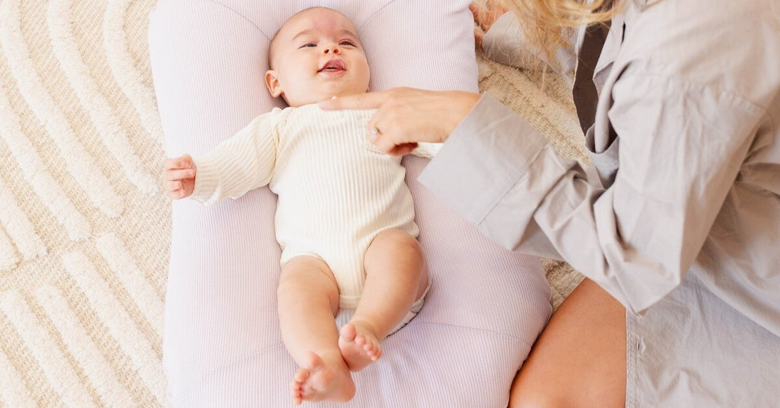 cute smiling baby on a lilac baby pod interacting with mum